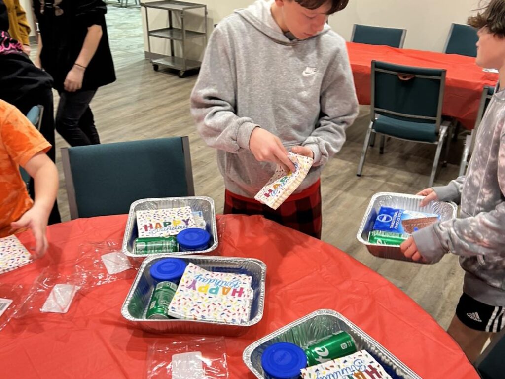 Children assembling birthday party kits on table.