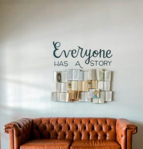 Wall art reading Everyone Has A Story above sofa