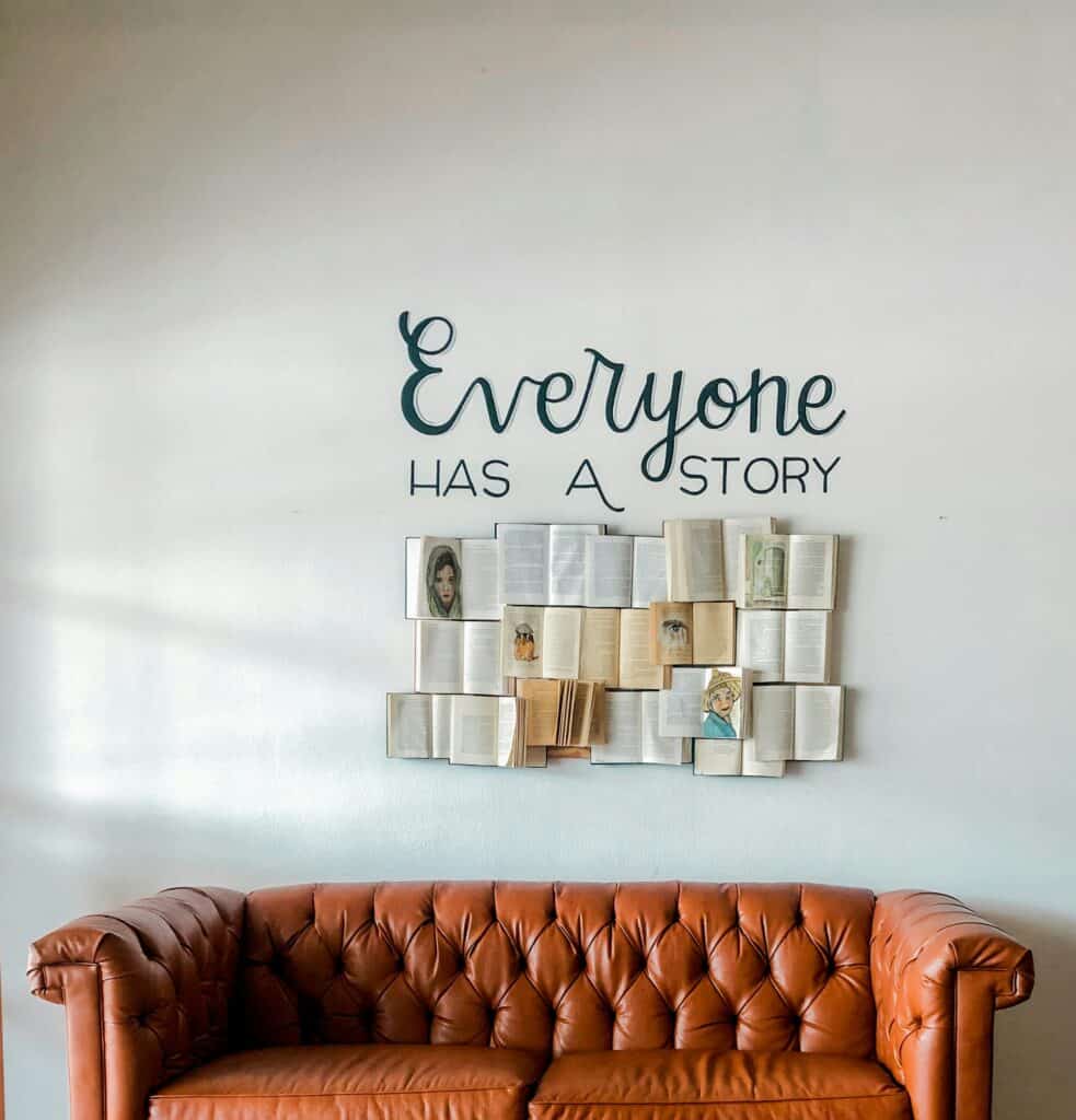 Wall art reading Everyone Has A Story above sofa